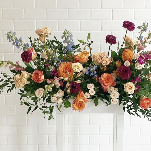 Large floral arrangement with peach, cream, and purple blooms