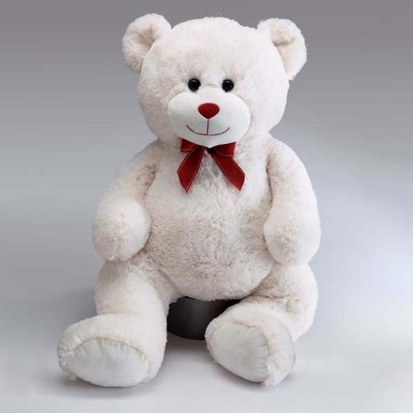 White teddy bear with a red bow sitting on a gray background