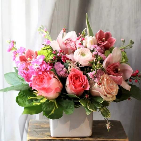 Pink and peach floral arrangement in a white vase