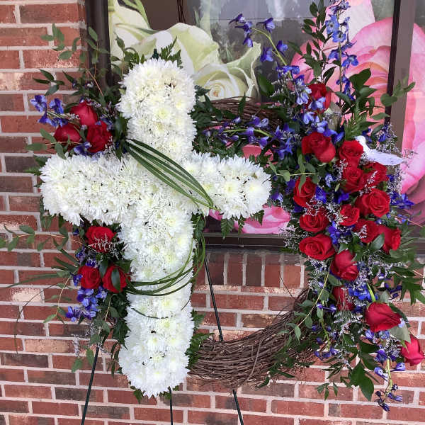 Two floral wreaths on stands, one white cross and one red rose heart