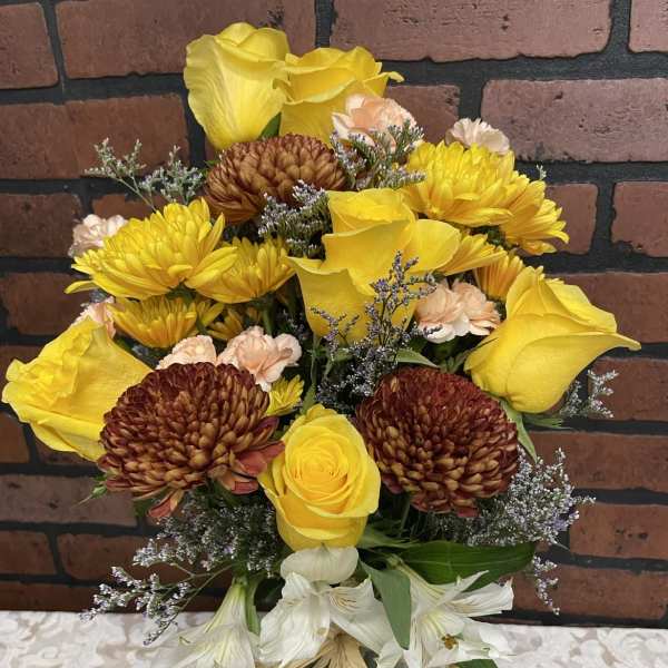 Yellow and white mixed bouquet with chrysanthemums and roses in a glass vase
