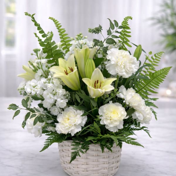 White lilies and carnations arranged in a white wicker basket