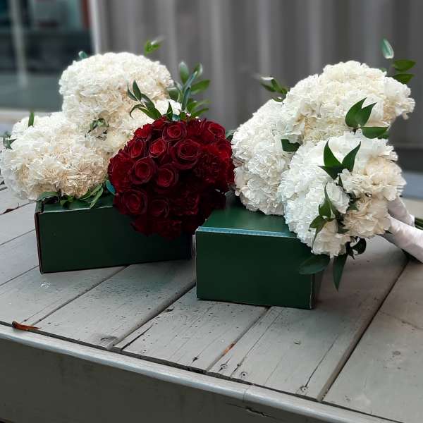 Bouquets of white carnations and red roses in green boxes
