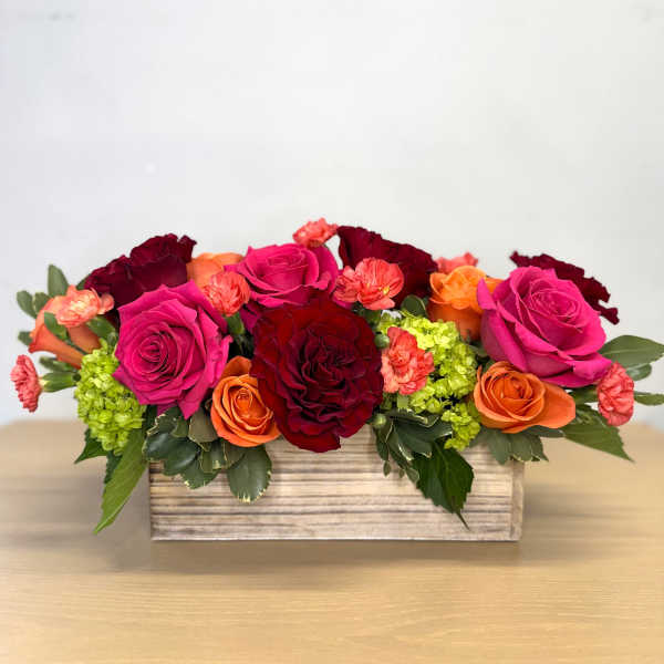 Rectangular floral arrangement with pink, red, and orange roses in a wooden box