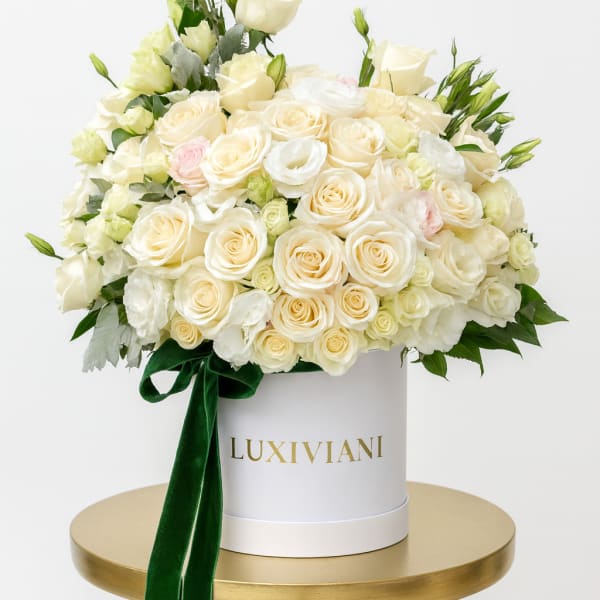 Cream rose arrangement in a white hat box with a green ribbon
