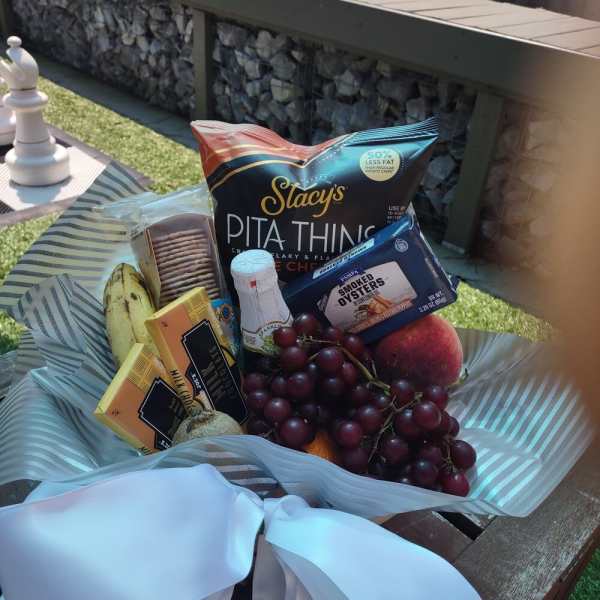 Gift basket with snacks, fruit, and a white ribbon