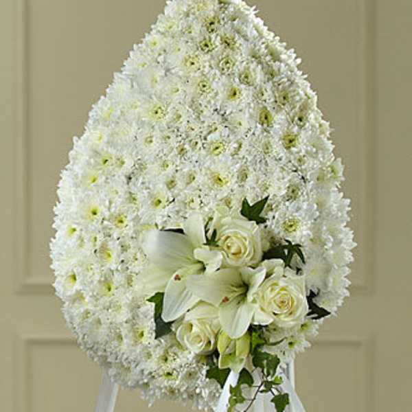White funeral spray with lilies and roses on an easel