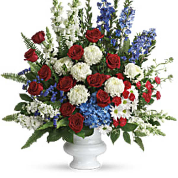 Red roses, white mums, and blue flowers in a white vase