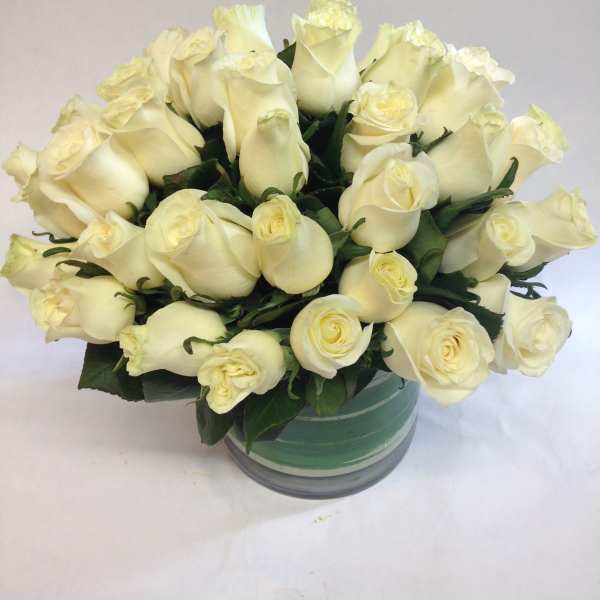 Bouquet of cream white roses in a round glass vase