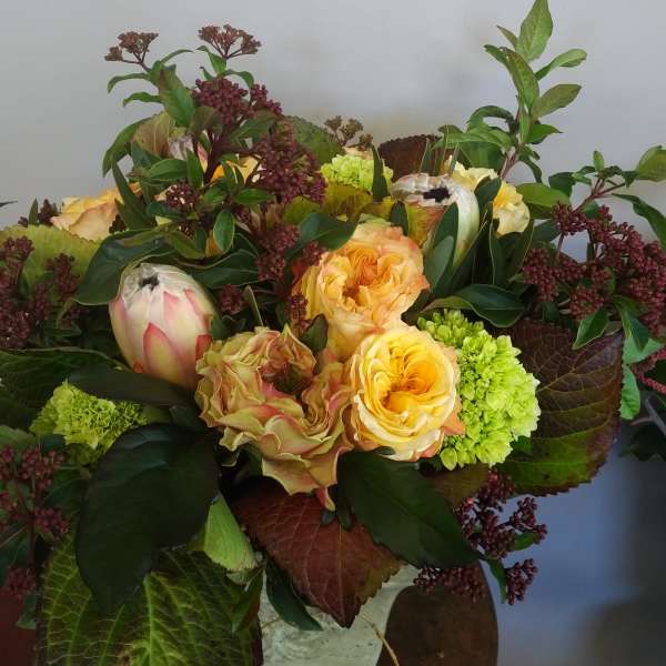 Bouquet of yellow roses and green blooms with burgundy foliage