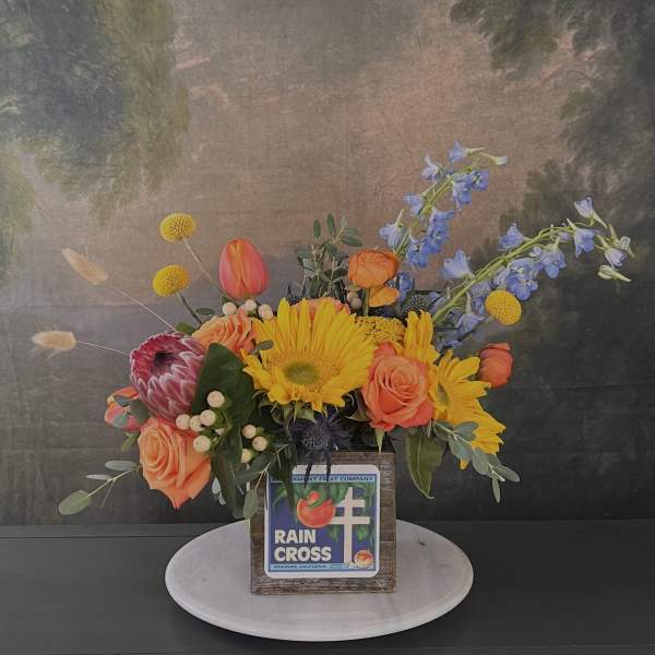 Colorful floral arrangement in a rustic wooden box with roses and sunflowers