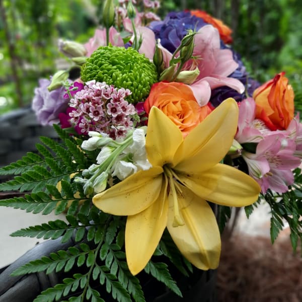 Colorful bouquet with yellow lily, orange roses, and pink blooms