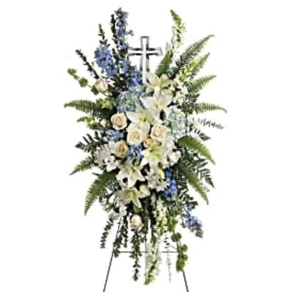 Standing funeral spray of white lilies and blue flowers on an easel