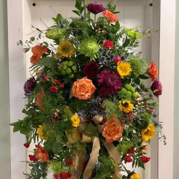 Tall colorful floral standing spray with ribbon on an easel