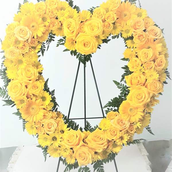 Yellow rose and daisy heart wreath on a black stand
