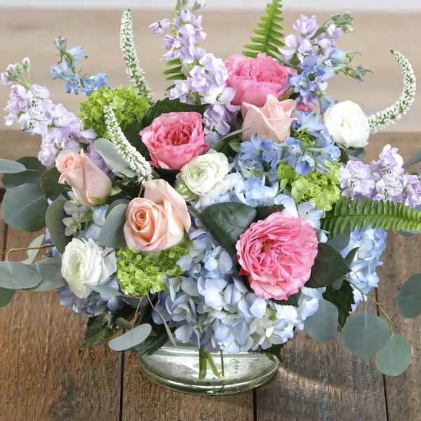 Pastel floral arrangement in a clear glass vase with roses and hydrangeas