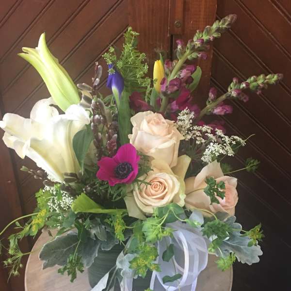 Mixed bouquet with roses, lilies, and purple blooms in a vase