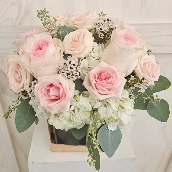 Bouquet of pale pink roses and white hydrangeas in a square vase