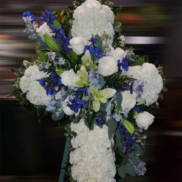 White floral cross on an easel with blue and green accents