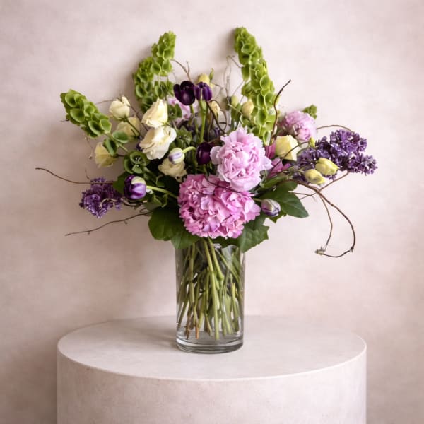 Mixed bouquet of pink, purple, and white flowers in a clear glass vase