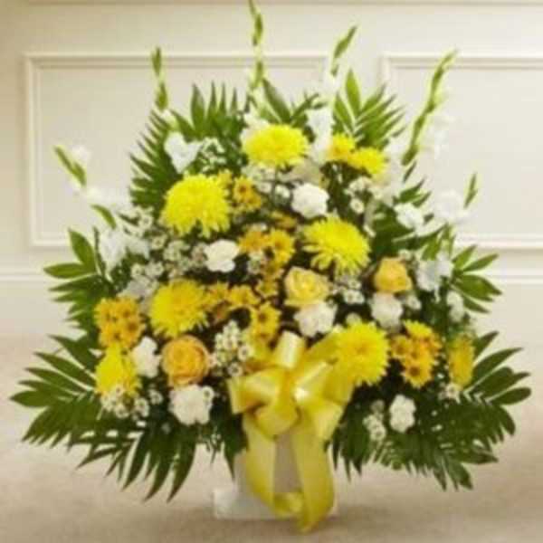Yellow and white floral standing spray with a yellow ribbon