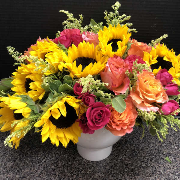 Bright sunflower and rose arrangement in a white vase