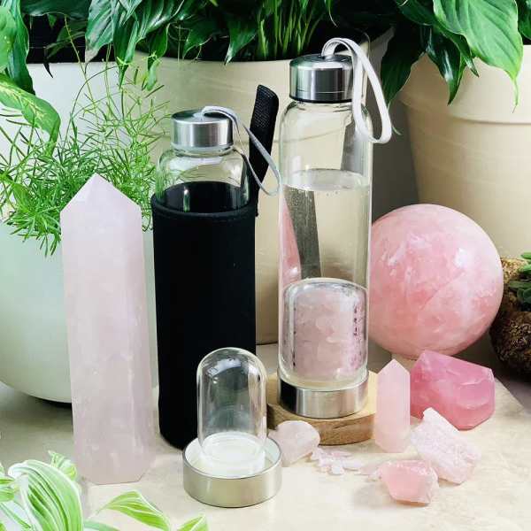 Crystal towers and pink stones arranged with glass water bottles and potted plants