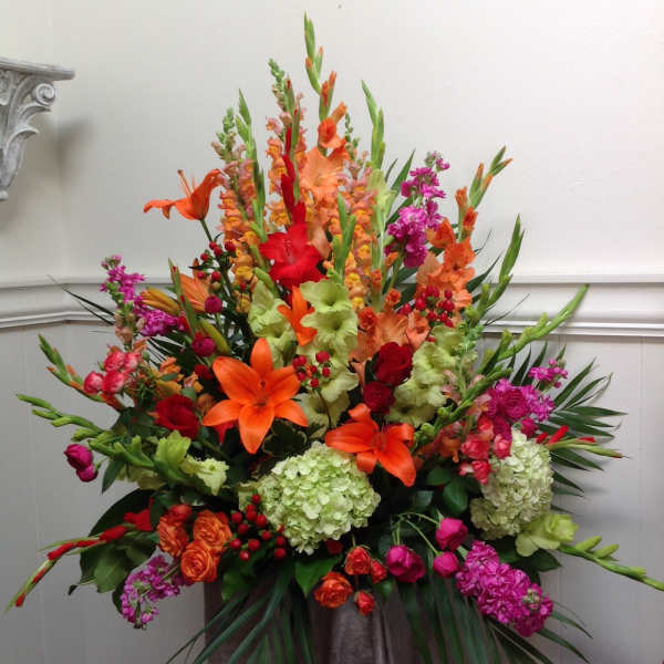 Large arrangement of orange, red, pink, and green flowers in a vase
