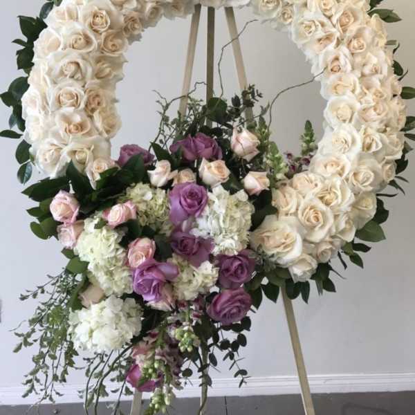 Large floral wreath of white and lavender roses on an easel