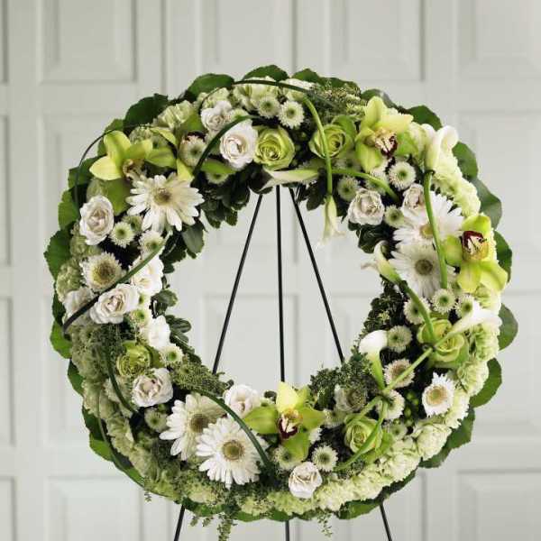 Circular floral wreath on a stand with white and green flowers