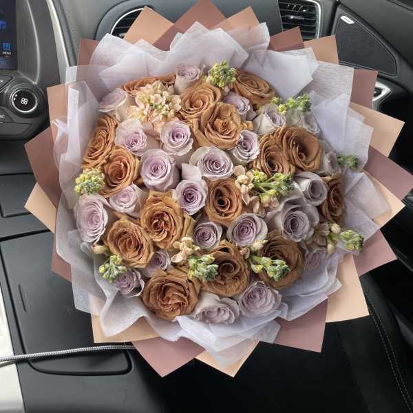 Bouquet of peach and lavender roses wrapped in pale paper