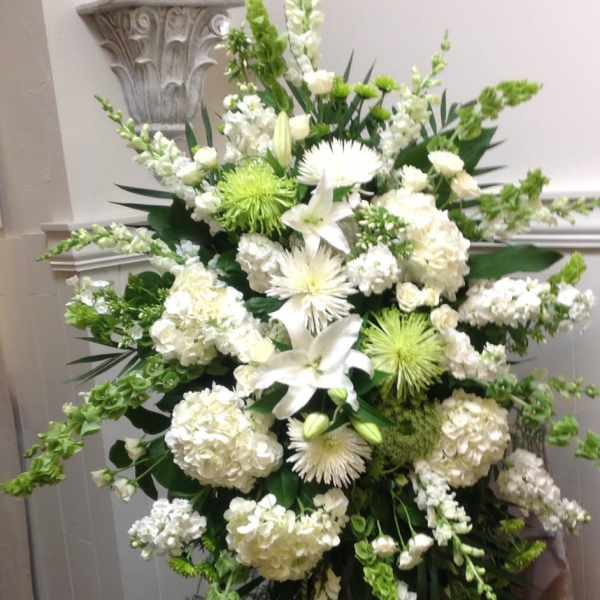 White funeral spray with lilies, hydrangeas, and green accents