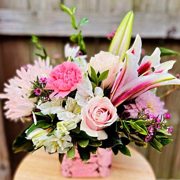 Pink and white mixed bouquet with lilies and roses in a pink vase
