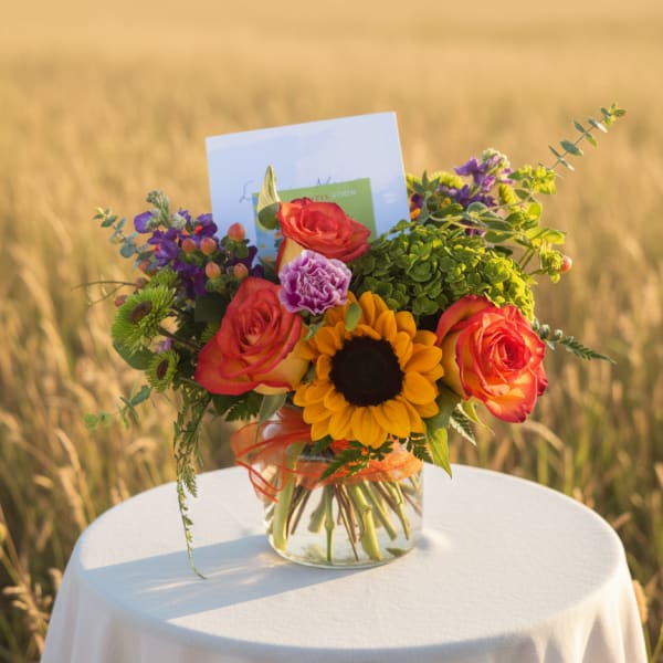 Bouquet of roses and a sunflower in a glass vase with a card