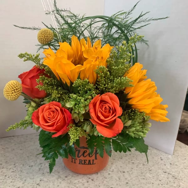 Orange and red roses with yellow blooms in a terracotta pot