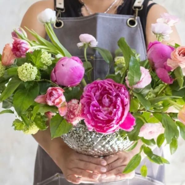 Pink and peach flowers arranged in a silver bowl vase
