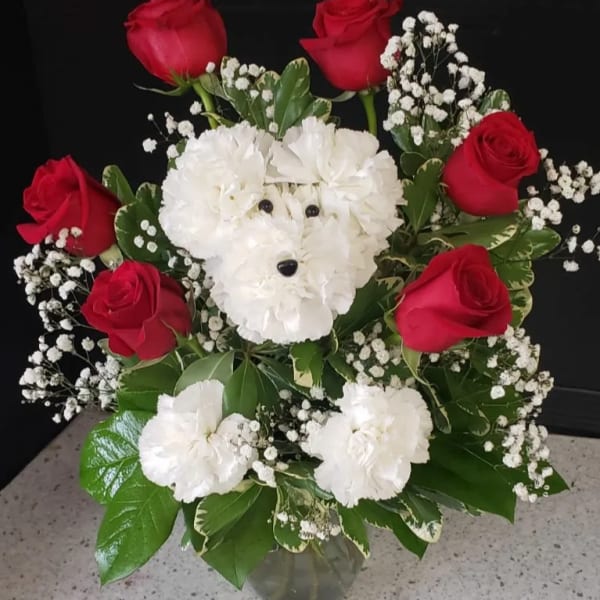 Red roses and white carnations arranged in a vase with baby's breath