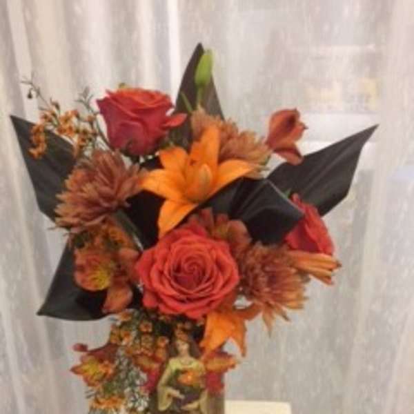 Orange and red floral arrangement in a vase with black wrap