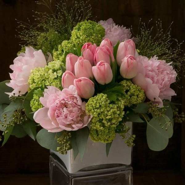 Pink tulips and peonies in a white square vase