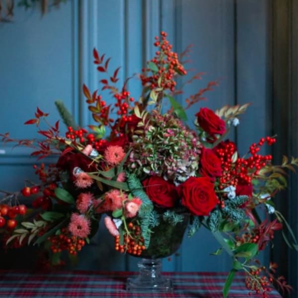 Red rose arrangement with berries in a glass vase