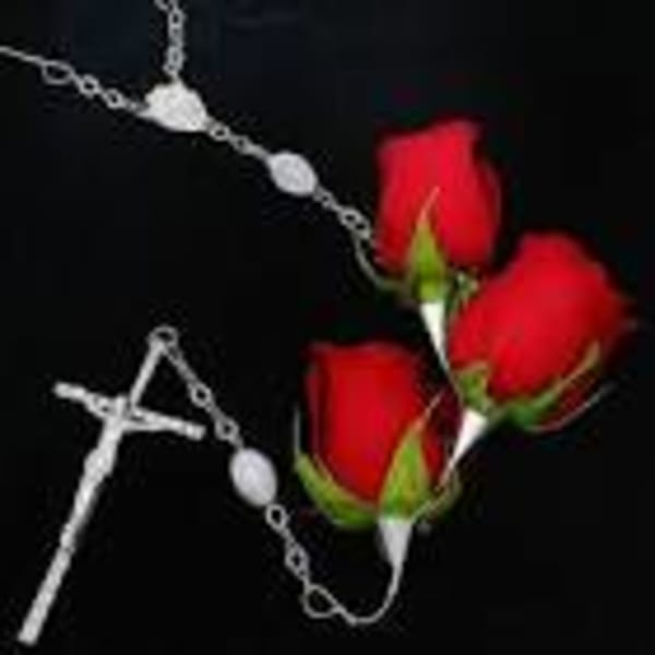 Three red rose buds with a silver rosary on a black background