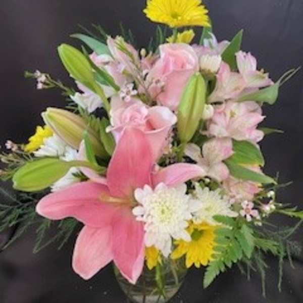 Pink lilies and roses with white daisies in a glass vase