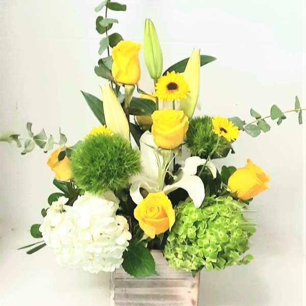 Yellow roses and white lilies in a wooden box with green accents
