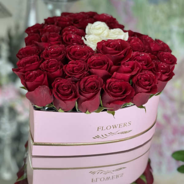 Red and white roses arranged in a pink hat box