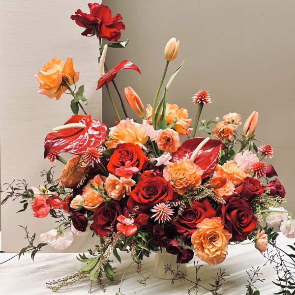 Red and orange floral arrangement with roses and anthuriums in a vase