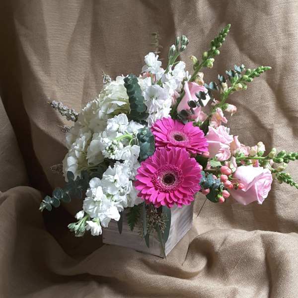 Pink gerbera daisies and white flowers in a small wooden box