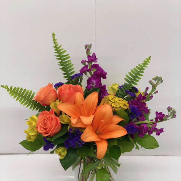 Orange lilies and coral roses in a clear glass vase