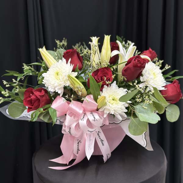 Red roses and white lilies with white chrysanthemums in a pink gift box