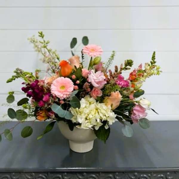 Mixed bouquet in a white vase with pink, orange, and white blooms