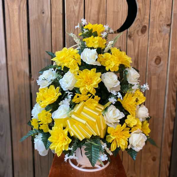 Tall arrangement of yellow and white silk flowers with a yellow striped bow in a white pot.